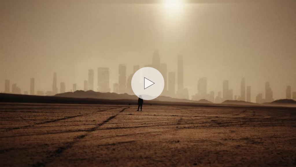 Silhouette of a person walking through the desert with the sun and skyscrapers in the background