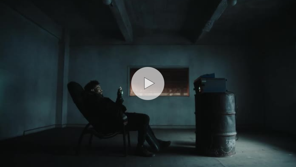 A man reclines in a chair in a room with a metal barrel in it